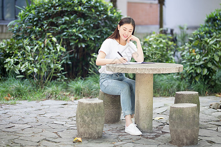 校园里坐在石凳上读书写字的女生图片