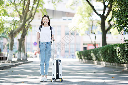 校园里拖着行李箱的女生背景图片