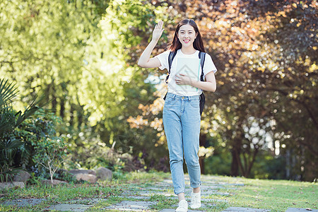 抱着书微笑招手打招呼的女性图片