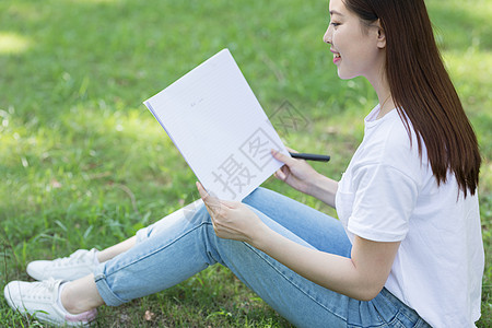 拿着课本坐在草坪上看书的大学生图片