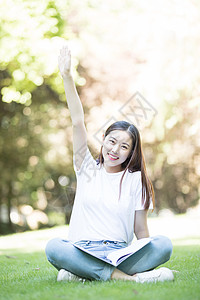 愉快地坐在草坪上学习的女同学图片