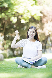 愉快地坐在草坪上学习的女同学图片