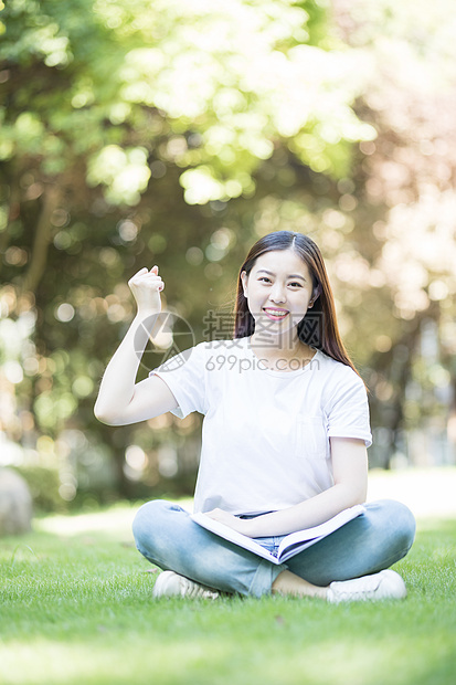 愉快地坐在草坪上学习的女同学图片