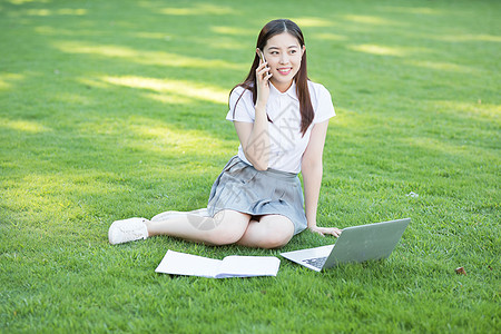坐在草坪上的打电话的女生图片