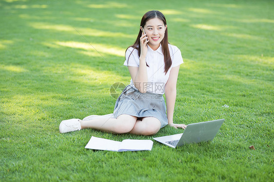 坐在草坪上的打电话的女生图片