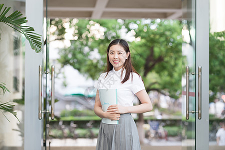 拿着课本站在校园里的女孩图片