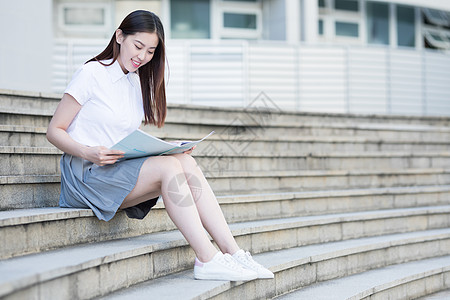 坐在学校台阶上看书的女同学图片