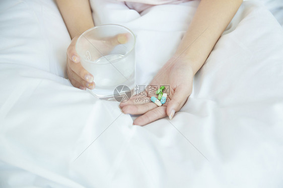 在床上吃药的女性手部特写图片