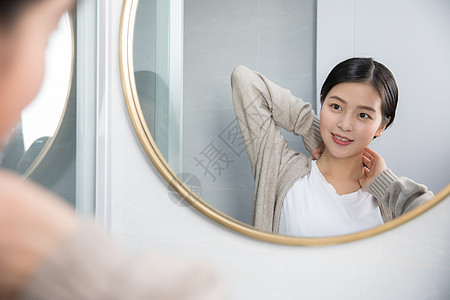 在家照镜子护肤美容的年轻女性图片