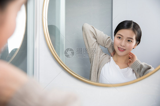 在家照镜子护肤美容的年轻女性图片