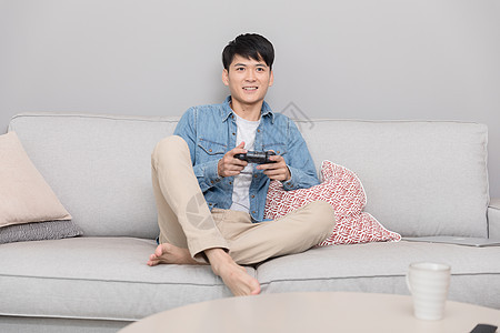 坐在沙发上玩游戏的男子背景图片