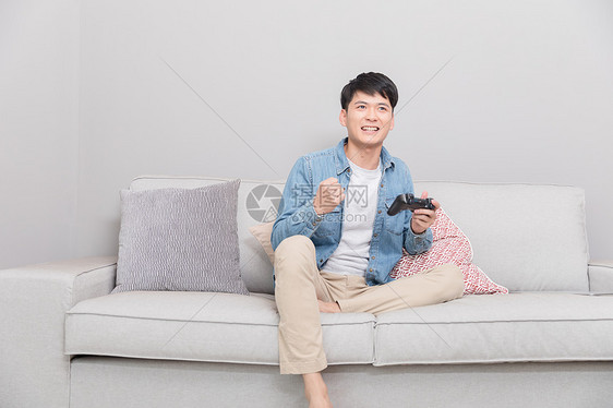 坐在沙发上玩游戏的男子图片