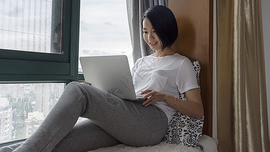女子坐在飘窗使用电脑背景图片