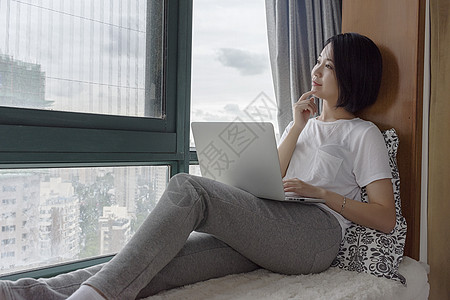 女子坐在飘窗使用电脑图片