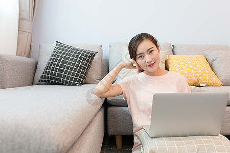 年轻美女靠着沙发玩电脑背景图片