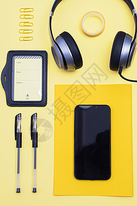 黄色背景上的数码产品和文具背景图片