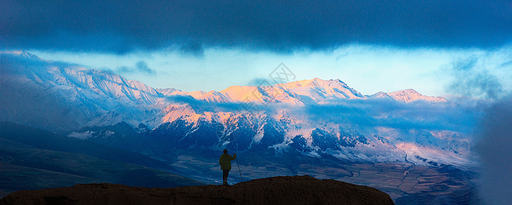 日照雪山与登山者图片