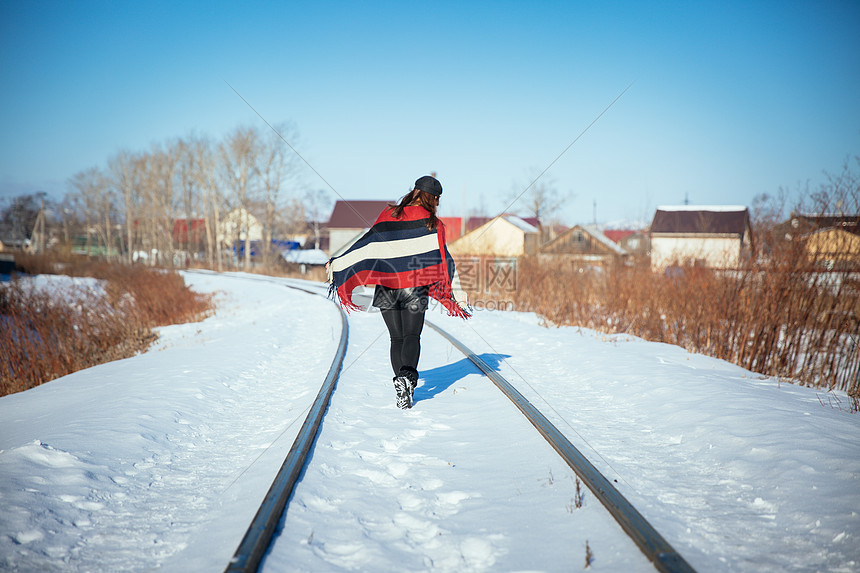 在冬天雪地铁轨上行走的女孩图片