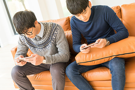 坐在客厅里玩手机的年轻人图片素材