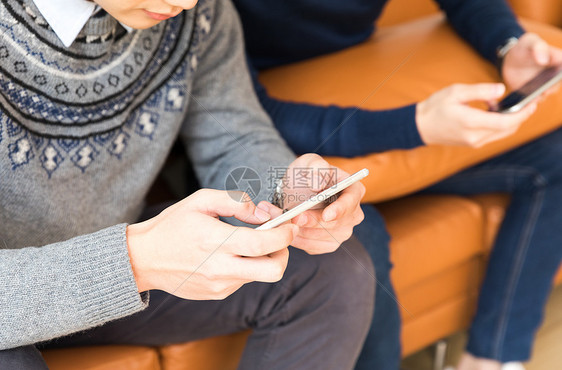 坐在客厅里玩手机的年轻人图片