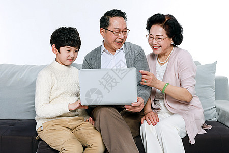 老人和孙子在沙发上玩电脑图片