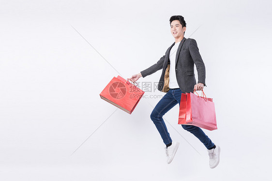 提着购物袋开心购物的年轻男子图片