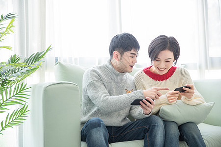 居家年轻情侣在沙发上玩手机游戏图片