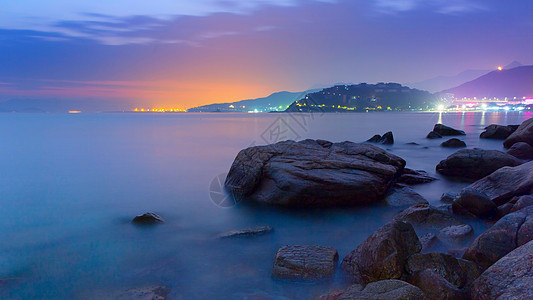 乱石滩与海边城市长曝夜景高清图片