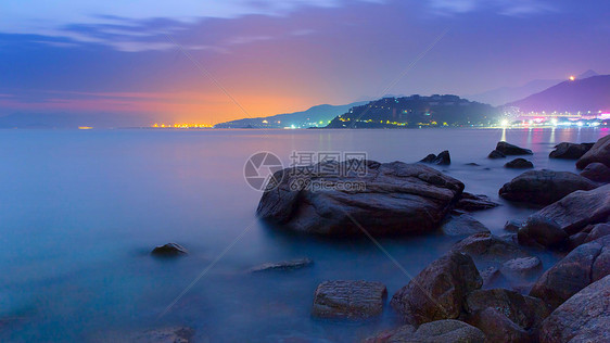 乱石滩与海边城市长曝夜景图片