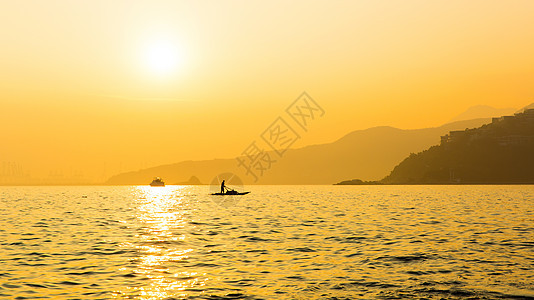 夕阳中海面船只与远山剪影图片