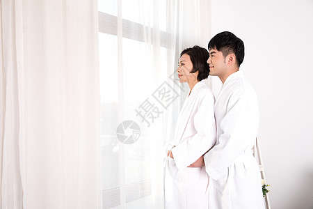 情侣穿着浴袍站在窗边背景图片