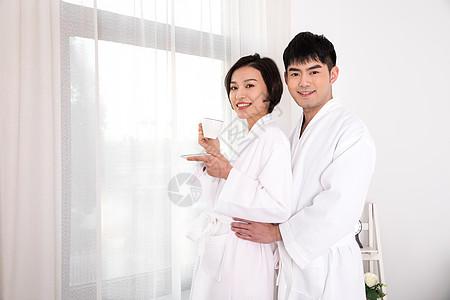 情侣穿着浴袍站在窗边图片