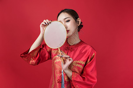 红色的梅花旗袍女性美妆手持蒲扇背景