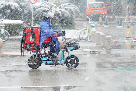 寒冷冬季马路骑电动车的外卖人员图片