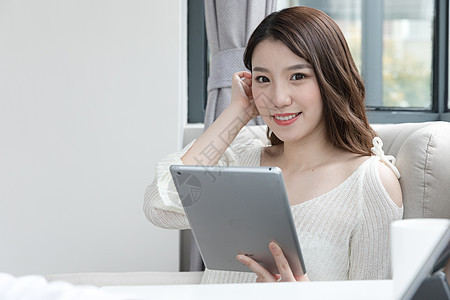 年轻女性在卧室放松看平板电脑背景图片