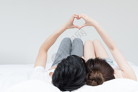 甜蜜情侣躺床上比心手势动作背景图片