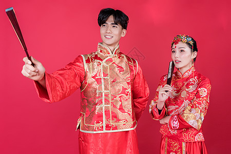 中式情人节情侣身着红妆手持扇子背景