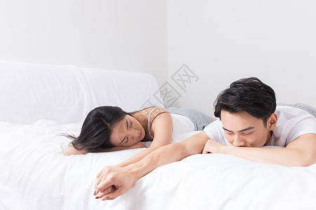 年轻夫妻牵手躺床上高清图片