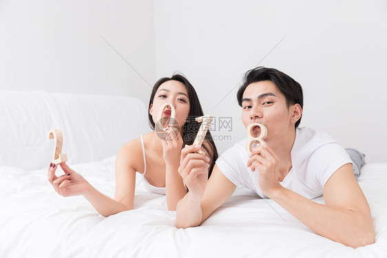 年轻夫妻开心躺床上手拿2018图片