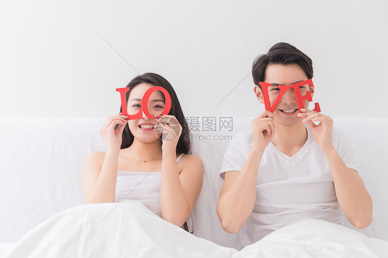 年轻夫妻靠床上手拿LOVE图片