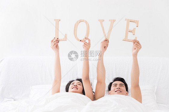 年轻夫妻躺床上手拿LOVE图片