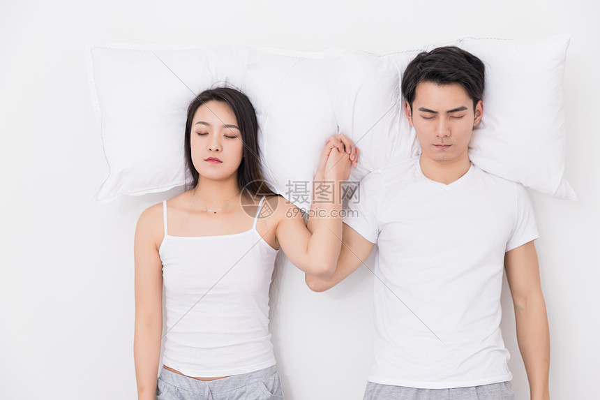 年轻夫妻枕着枕头在一起图片