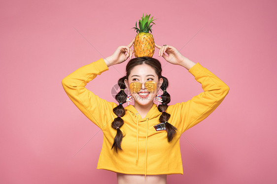 年轻双马尾女性头顶菠萝图片