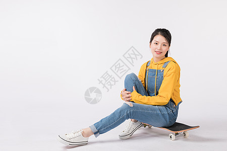 坐在滑板上的青春美少女背景图片