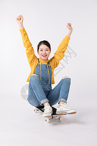 坐在滑板上欢呼的年轻女生图片