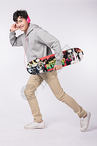 边玩滑板边听音乐的帅气男生图片