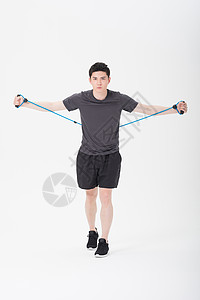 青年男子使用阻力带健身塑身图片