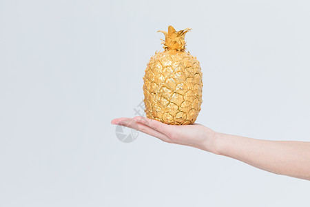 金色的菠萝手托创意金菠萝背景