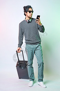 休闲男性色彩创意推着拉杆箱拿着手机图片