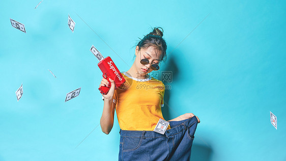 青年时尚女性手持喷钱枪图片